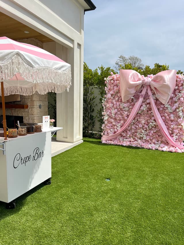 Crepe bar cart beside a giant pink bow flower wall